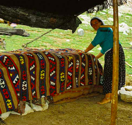 Sarıkeçili Turkmen tribeswoman showing the kilim she wove, covering the nomadic sacks in the tent. kdağ Pasture, Fethiye, South-Western Turkey, 180s, photo courtesy Josephine Powell, Suma Kıraç Foundation